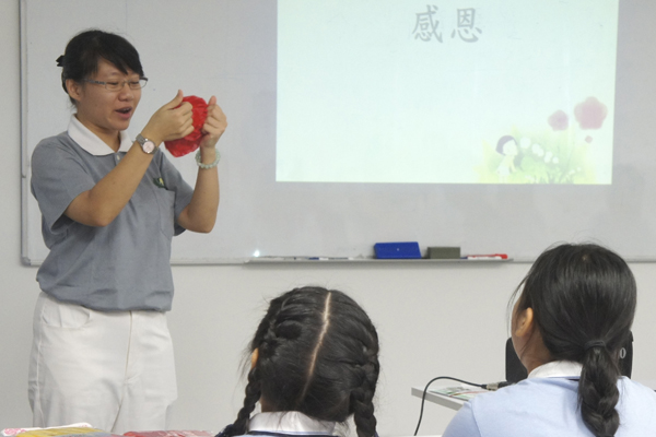 学生正专注地聆听志工许毓宝讲解制作手工花的步骤。摄/陈润娇